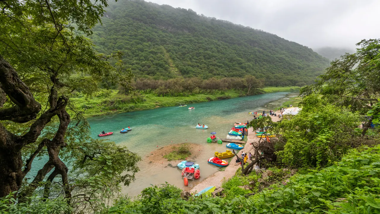 Visitors enjoying a turquoise river beneath lush green hills