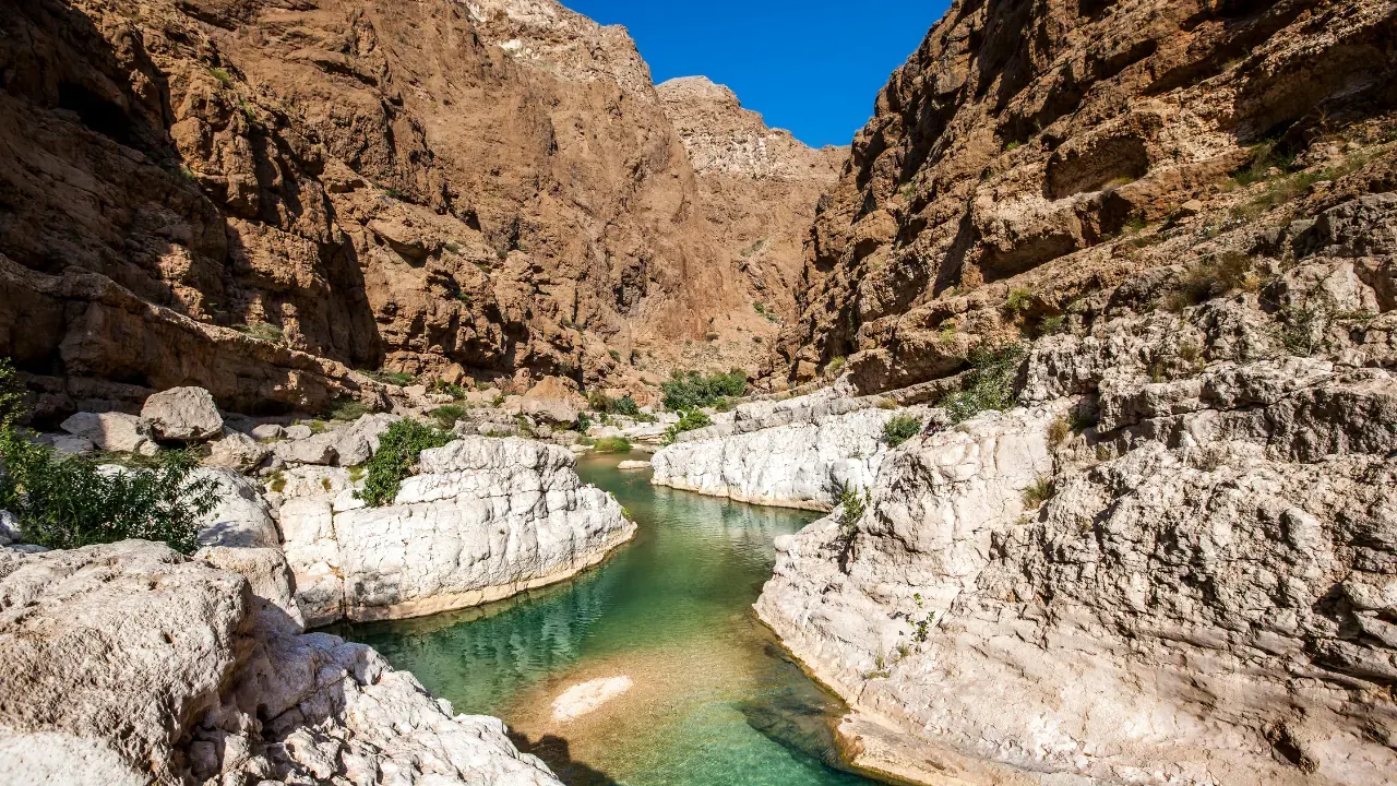 Emerald pool between steep sunlit rock walls