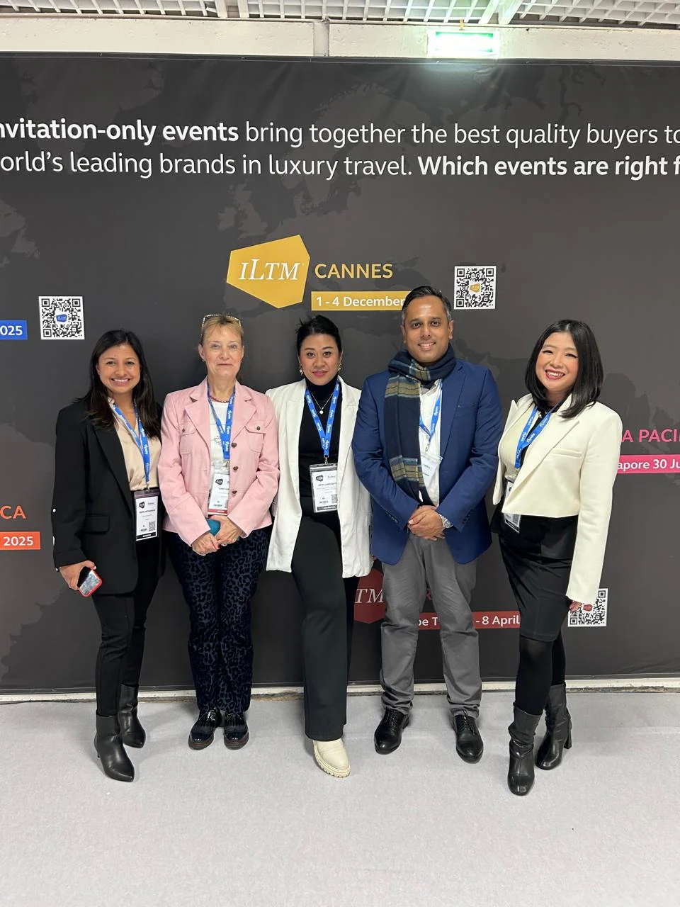 Travel delegates posing together in front of an event backdrop
