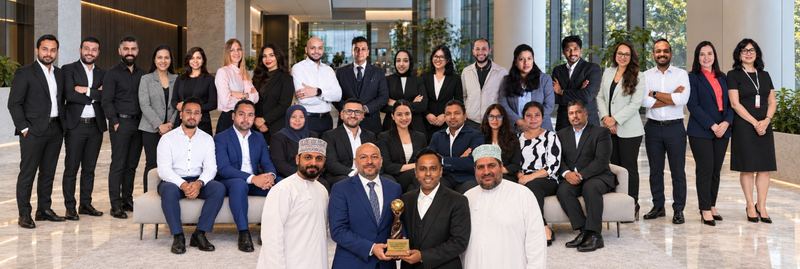 The Miracle Oman team gathered around an award in Muscat